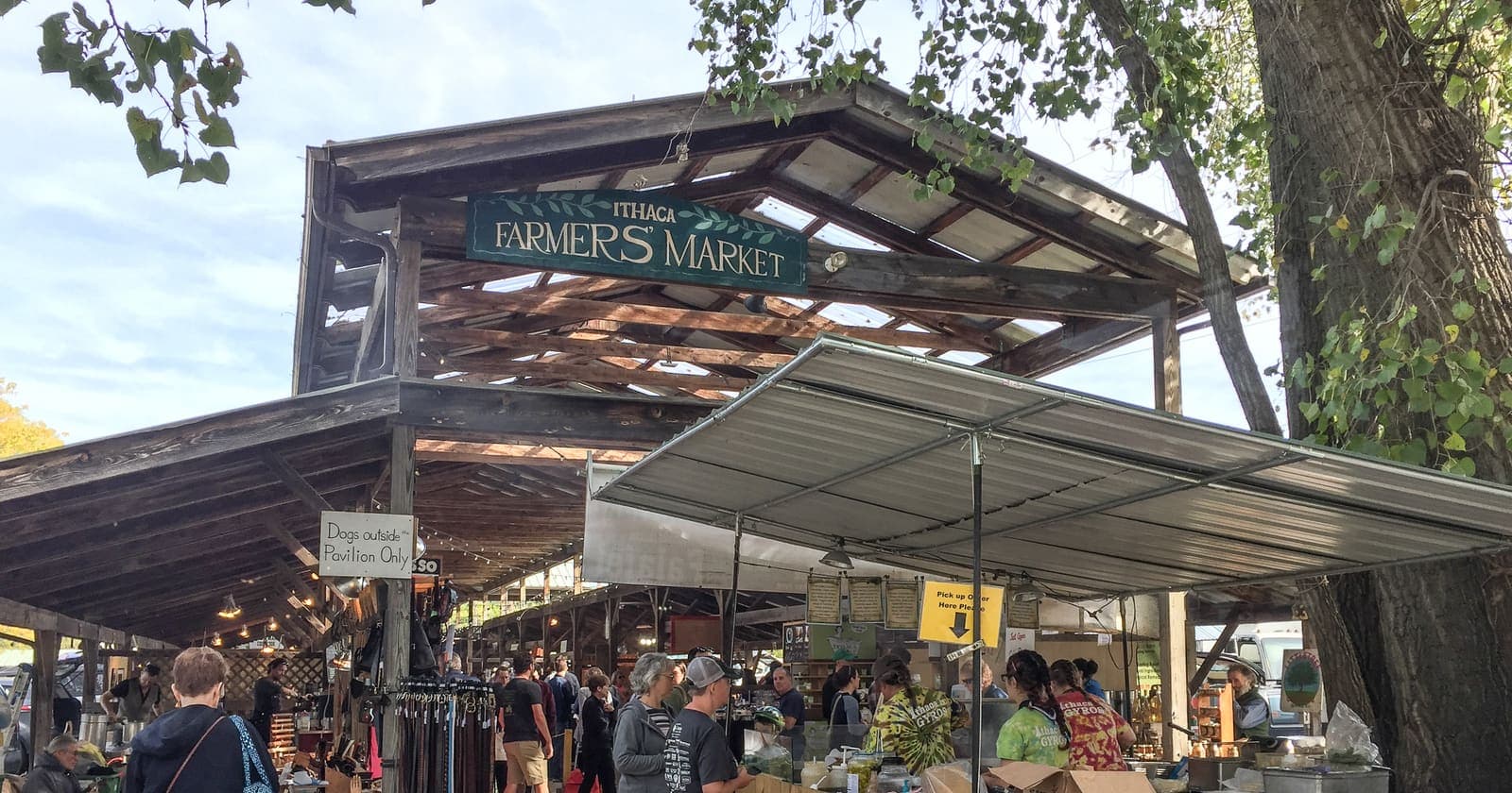 Shoppers under the wooden pavilion of the Ithaca Farmers Market at Steamboat Landing in Ithaca, New York, on an October morning